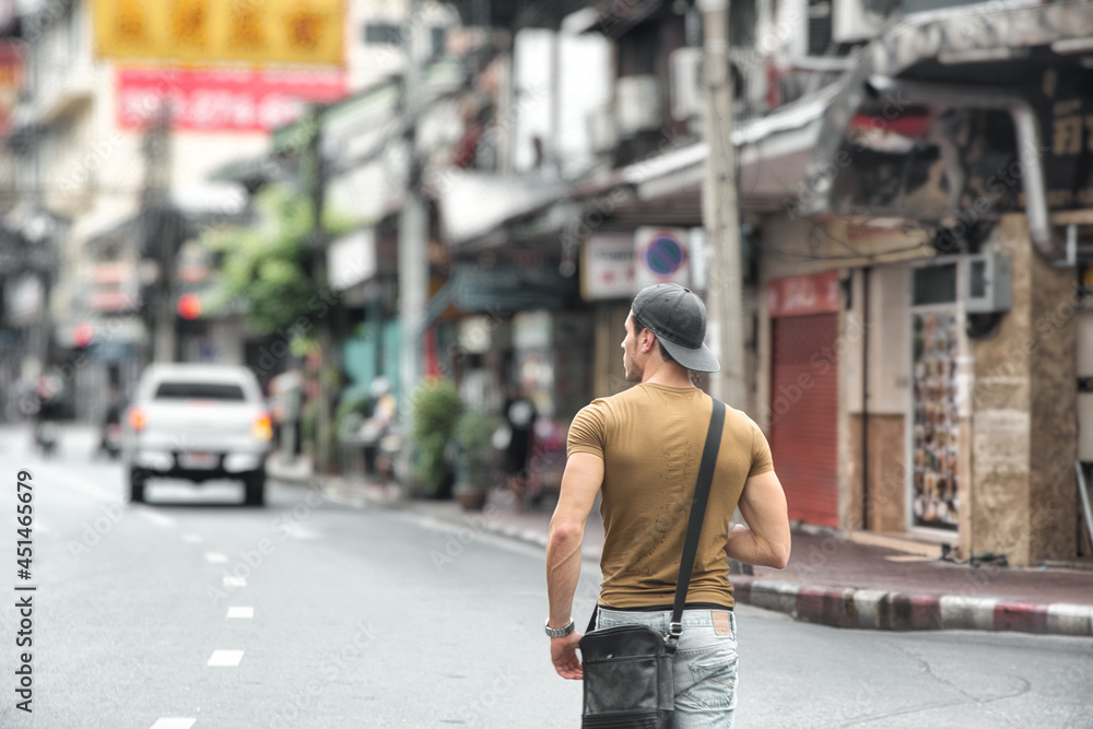 Back view of young man walking in Bangkok, Thailand Back view of young man walking in Bangkok, Thailand