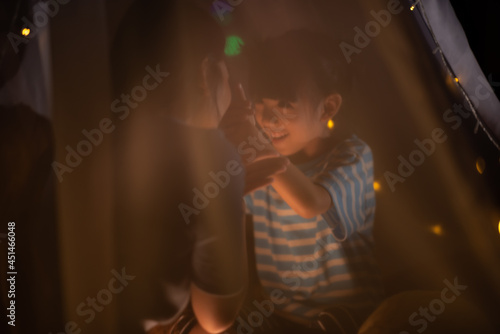 a little girl playing hand shadow art with her mom in bedroom before sleeping time, family concept, cute kid smiling, asian family concept, playing in kid tent.