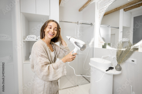 Woman dries hair with a hair dryer in a modern bathroom