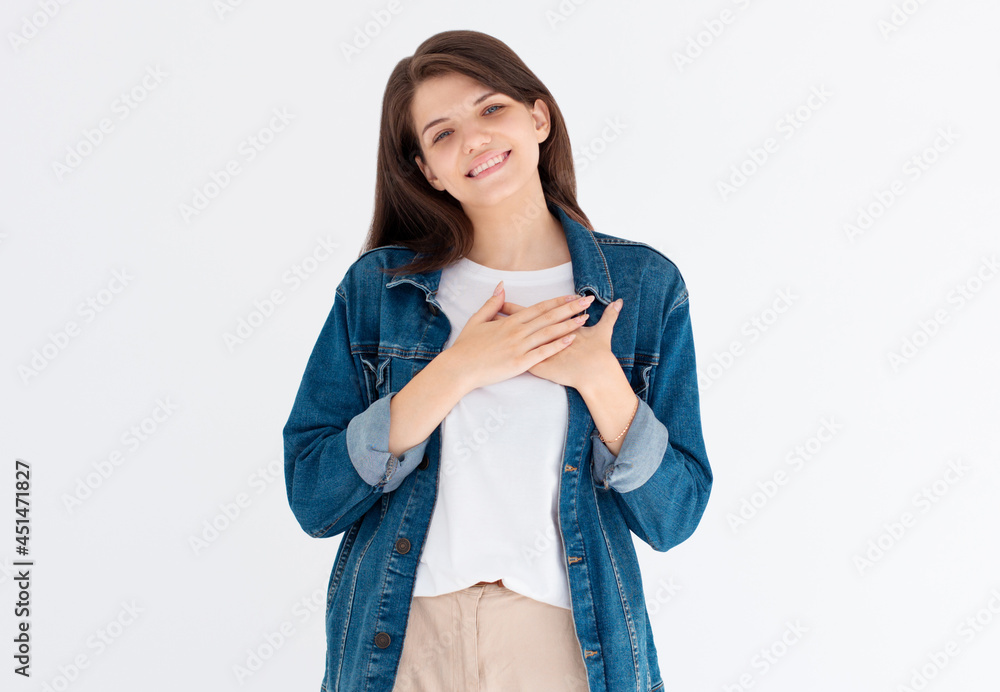 Beautiful positive friendly-looking young european woman showing her heart filled with love and gratitude holding hands on her breast Beautiful positive friendly-looking young european woman showing her heart filled with love and gratitude holding hands on her breast