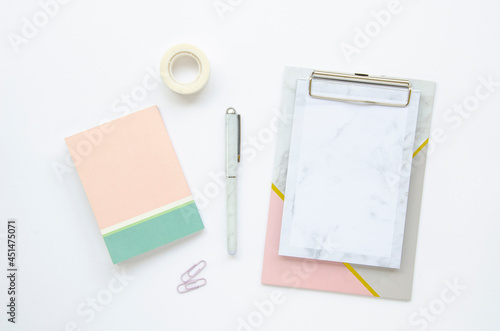 Desktop. Pink notepad, pen, scotch tape and paper clips on a white background. Top view