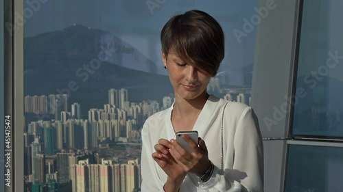 Pretty businesswoman using smart phone in high-rise modern office. photo