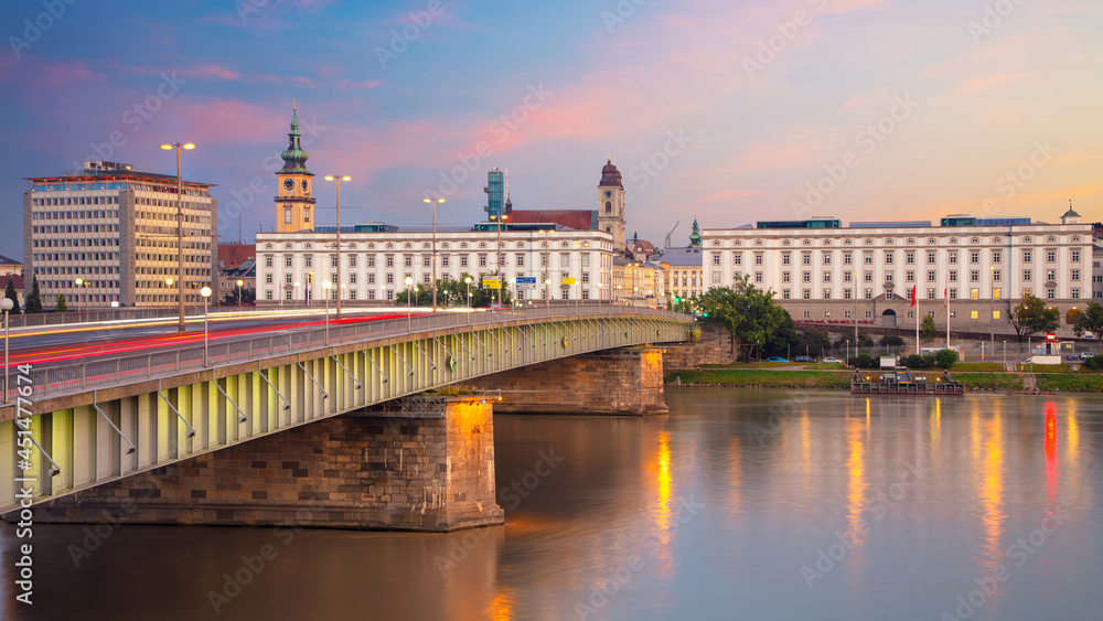 Linz, Austria. Panoramic cityscape image of riverside Linz, Austria during twilight blue hour with reflection of the city lights in Danube river.