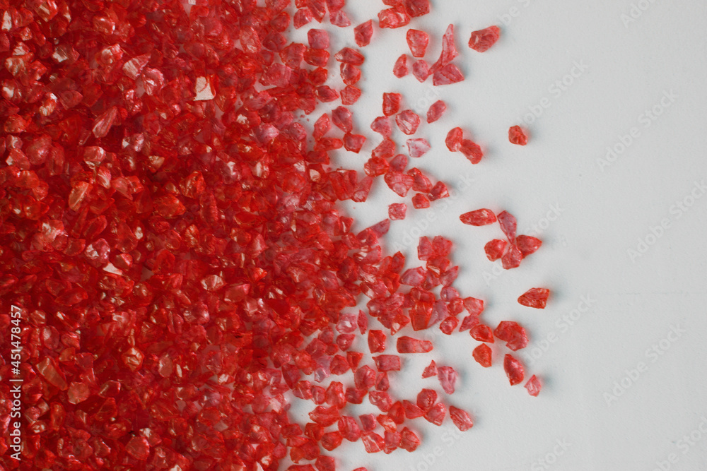 Glass small stones scattered on white surface. Red glass gems pattern, space for text. Glass small stones scattered on white surface. Red glass gems pattern, space for text.