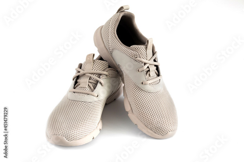Beige women's casual sneakers are isolated on white background. Pair of summer shoes for travel, sports and everyday life