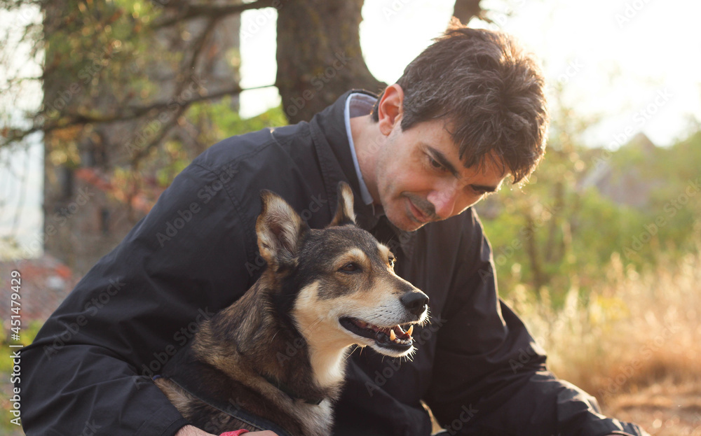 happy muzzle of a dog sitting next to the owner, surrounded by the blurry rays of a sunny sunset happy muzzle of a dog sitting next to the owner, surrounded by the blurry rays of a sunny sunset