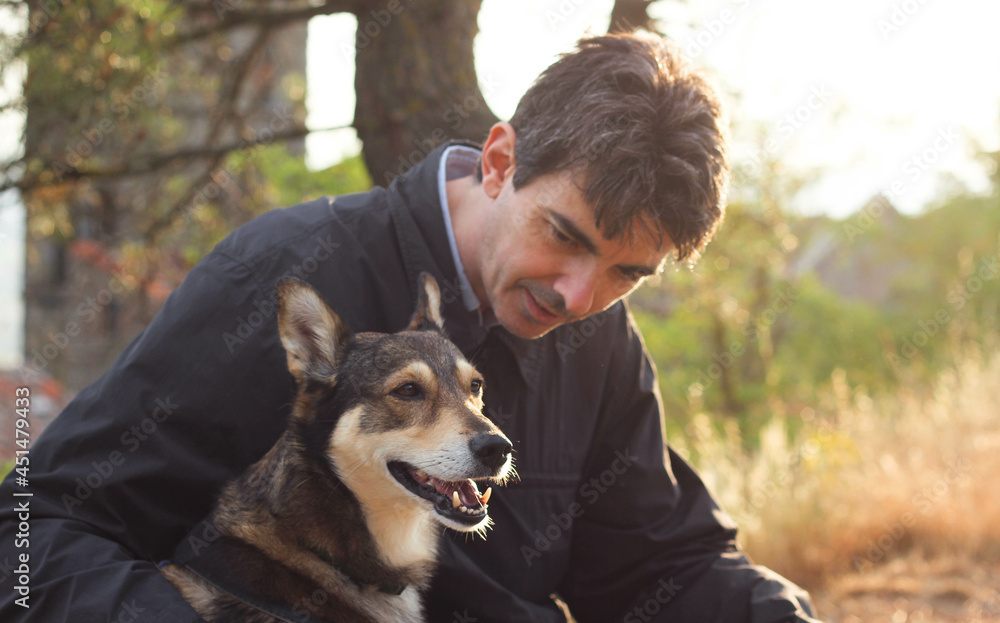 happy muzzle of a dog sitting next to the owner, surrounded by the blurry rays of a sunny sunset happy muzzle of a dog sitting next to the owner, surrounded by the blurry rays of a sunny sunset