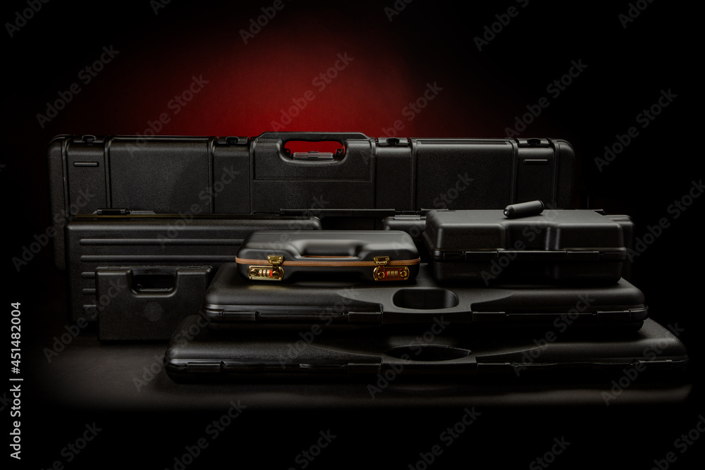A variety of plastic cases for weapons. Strong containers for storing and transporting weapons against a dark background with a red spot of light. A variety of plastic cases for weapons. Strong containers for storing and transporting weapons against a dark background with a red spot of light.