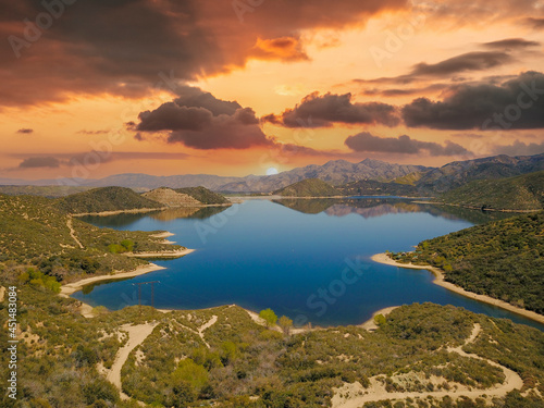 a majestic aerial panoramic shot of the vast blue still lake water with breathtaking mountain ranges reflecting off the lake at sunset at Silverwood Lake in Hesperia California USA photo