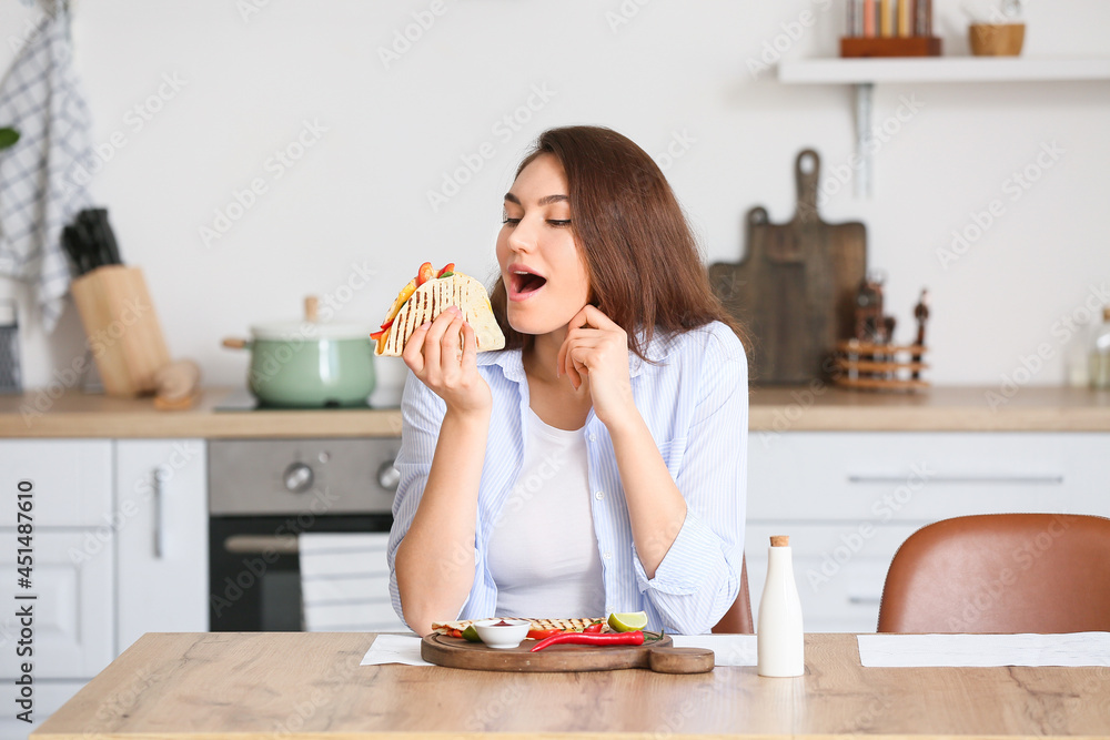 Beautiful young woman eating tasty quesadilla at home Beautiful young woman eating tasty quesadilla at home