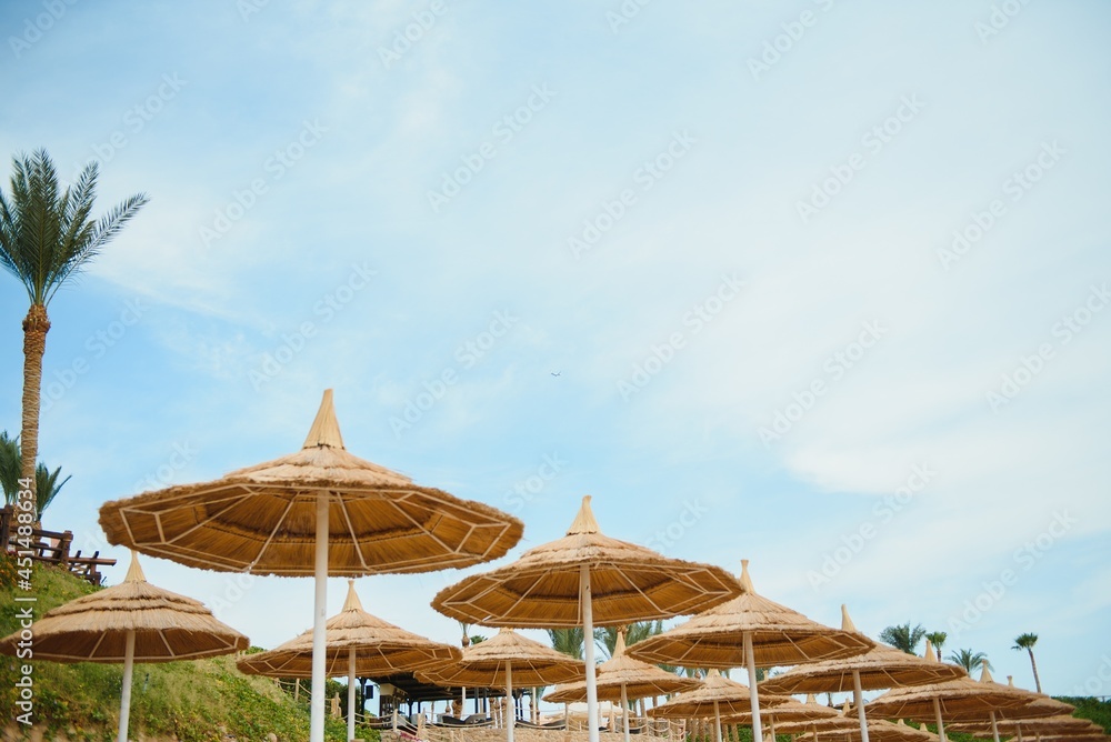 Umbrella and deck chair around outdoor swimming pool in hotel resort with sea ocean beach and coconut palm tree