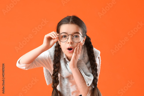 Shocked little school girl on color background