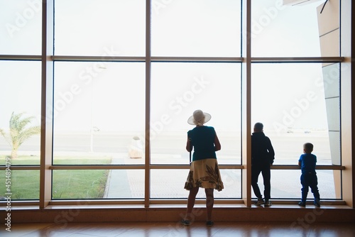 Family at airport before flight. Mother and kids waiting to board at departure gate of modern international terminal. Traveling and flying with children. Mom with baby and toddler boarding airplane.