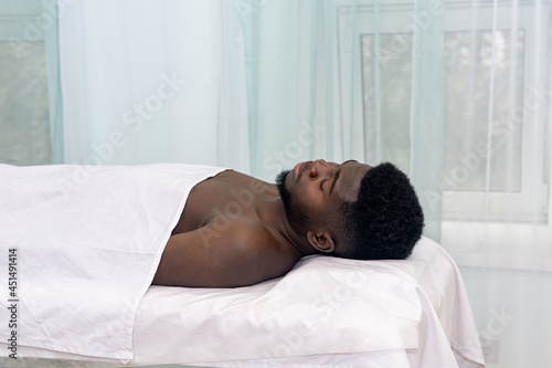 black man lying on a bed in a medical facility