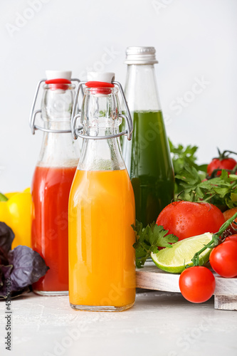 Fototapeta Naklejka Na Ścianę i Meble -  Bottles with healthy juice, fruits and vegetables on light background