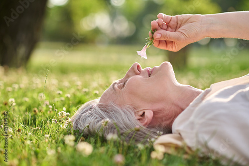 Woman admiring flower lying on grass photo