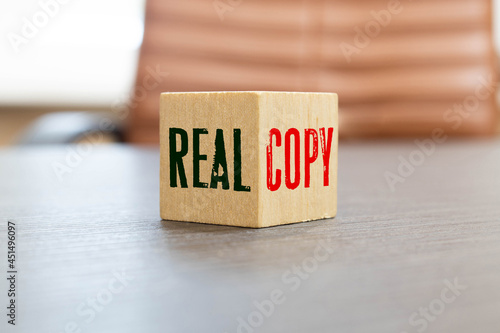 Wooden blocks form the words 'real copy', miniature wooden houses.
