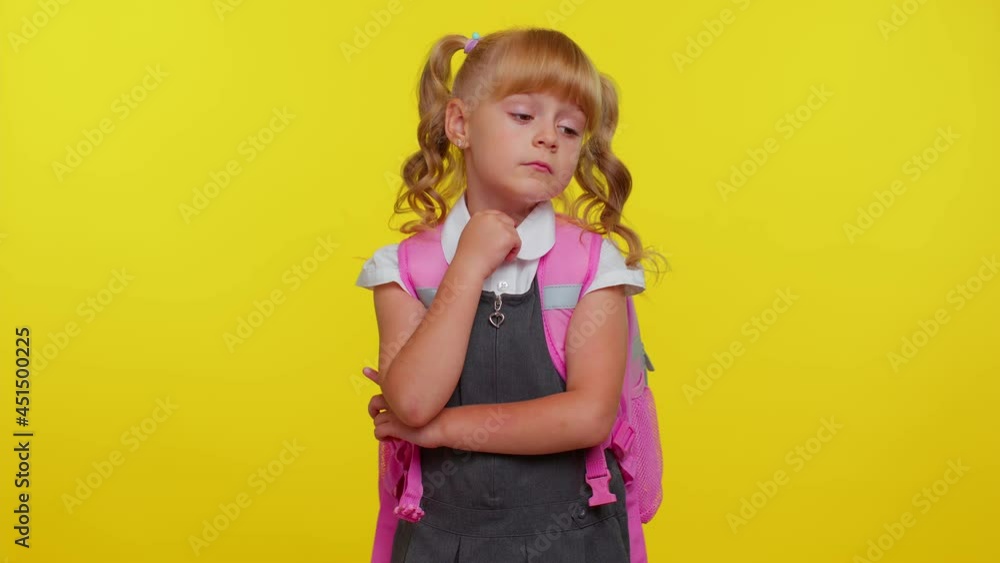 Thoughtful clever blond teenage girl dressed in school uniform rubbing her chin and looking aside with pensive expression, pondering a solution, doubting question over yellow studio wall background Thoughtful clever blond teenage girl dressed in school uniform rubbing her chin and looking aside with pensive expression, pondering a solution, doubting question over yellow studio wall background
