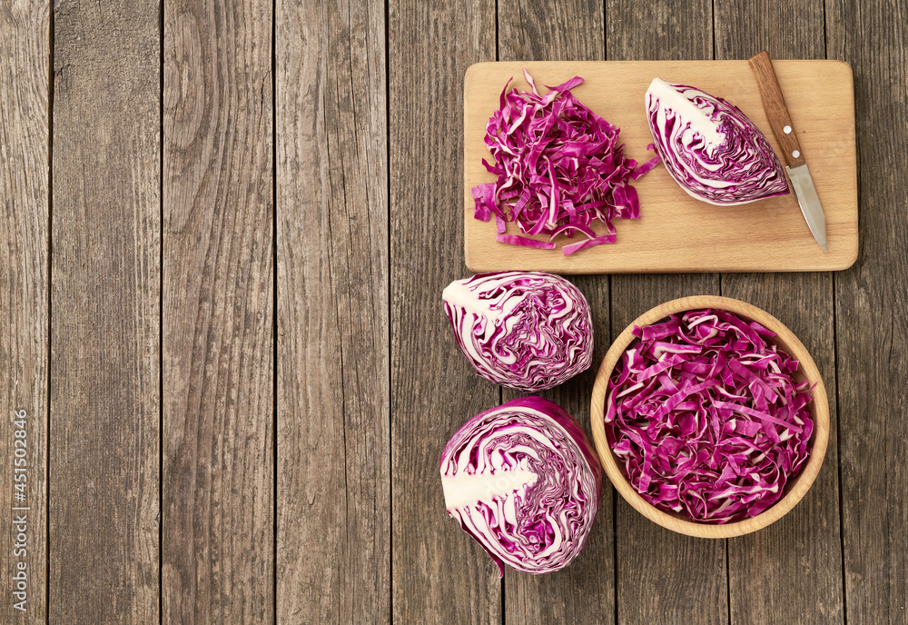 Whole and sliced red cabbage on a cutting board, top view.