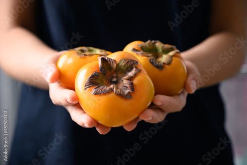 Ripe persimmon fruit holding by woman hand, Healthy Eating photo