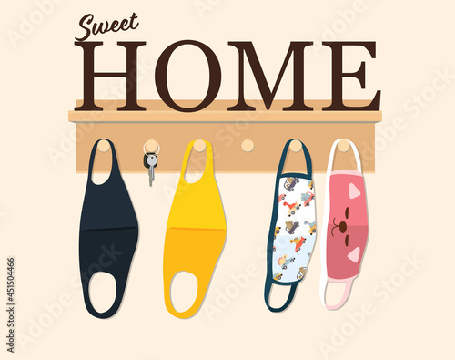 Wooden hanger for keys and family cloth face masks on light wall with sweet home text decoration