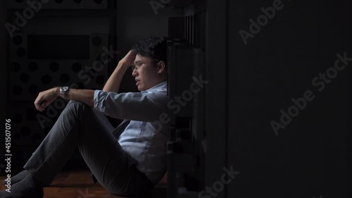Stressed Asian businessman sitting on the floor holding financial bill think of debt and business problem. Unemployed man worry about money management. Mental health and financial problem concept photo