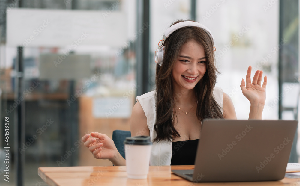 Φωτογραφία Smiling girl student wear wireless headphone study online with teacher, happy young asian woman learn language listen lecture watch webinar write notes look at laptop sit in cafe, distant education