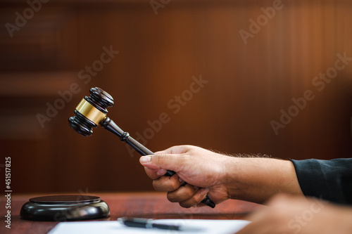 closeup hand Judge with gavel at wooden table indoors at the courtroom photo