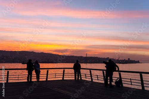Silhouette of people enjoying the sunset on main pier of Valparaiso, Chile.