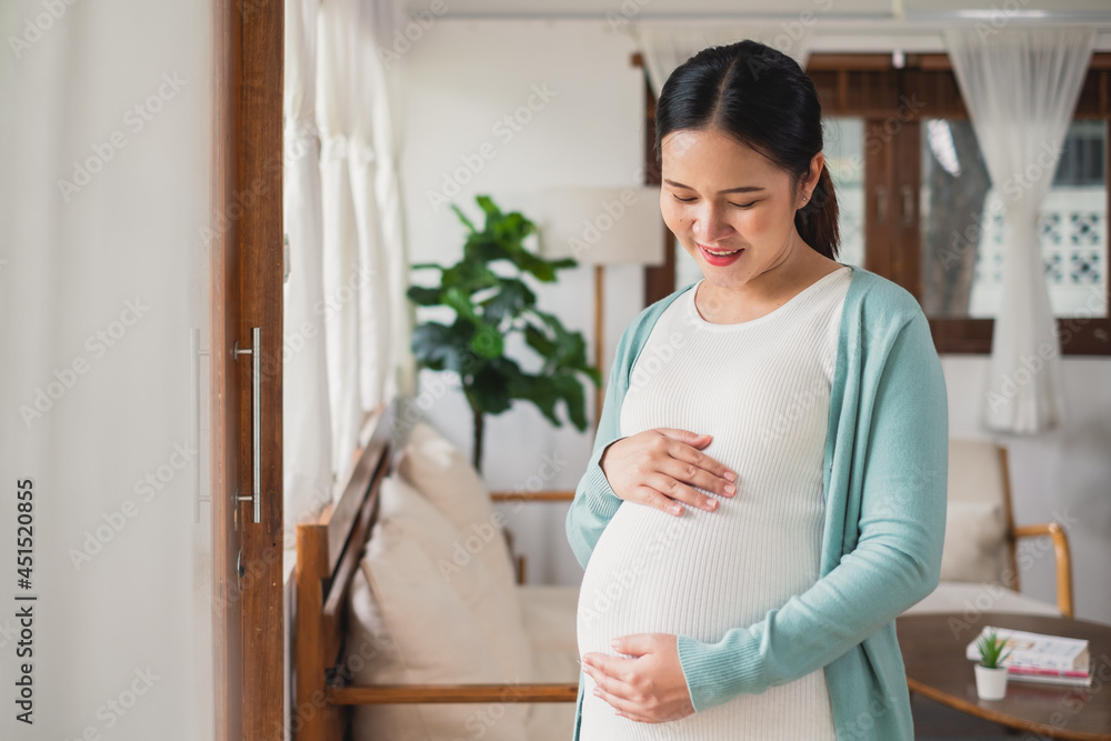 © Nattakorn - Asian young pregnant woman smile with big belly at home