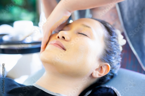 A beautiful Asian woman is sleeping while the attendant massages her face with turmeric powder. Gently cleanse face.
