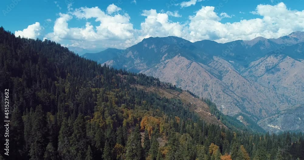 aerial drone shot of forest and high altitude mountains. blue sky yellow and green trees. beautiful cloud scape. aerial drone shot of forest and high altitude mountains. blue sky yellow and green trees. beautiful cloud scape.