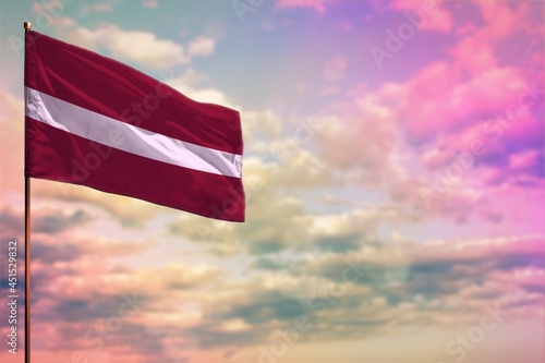 Fluttering Latvia flag mockup with the space for your content on colorful cloudy sky background. photo