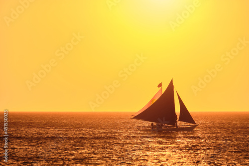 Boracay, Philippines - Jan 23, 2020: Sunset on Boracay island. Sailing and other traditional boats with tourists on the sea against the background of the setting sun.
