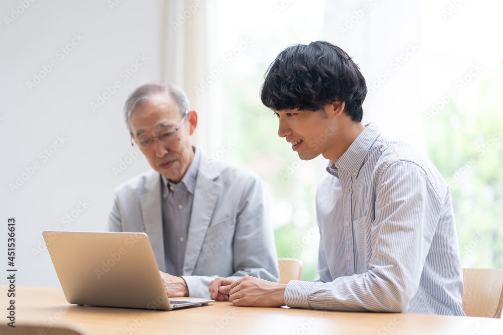 パソコンを見る若い男性とシニア