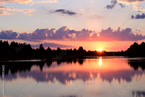 Beautiful summer sunset and pink sky over the river. Clouds are reflected in the calm water. Beauty in this world