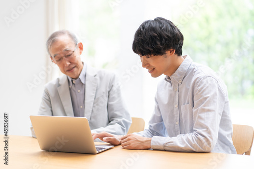 パソコンを見る若い男性とシニア