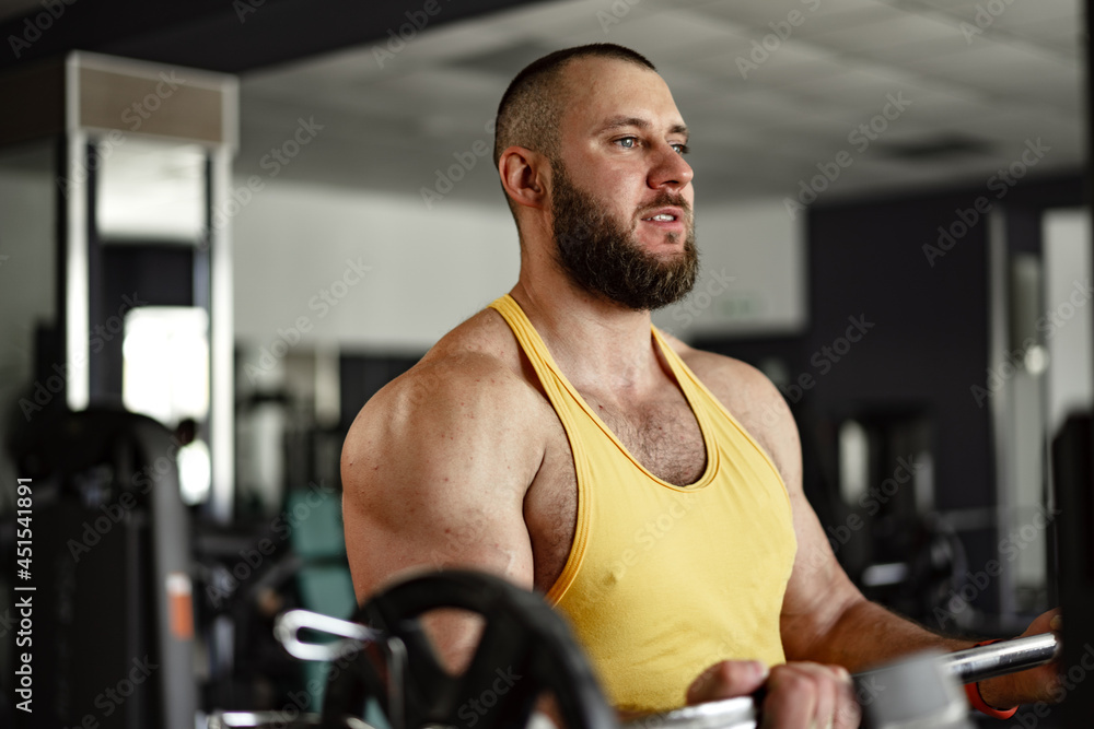 Cheerful smiling man bodybuilder standing in a gym