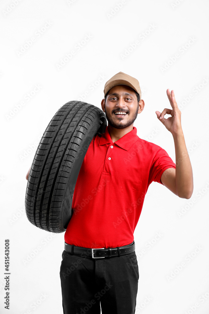 Handsome young male mechanic with new tires isolated on white background. Handsome young male mechanic with new tires isolated on white background.