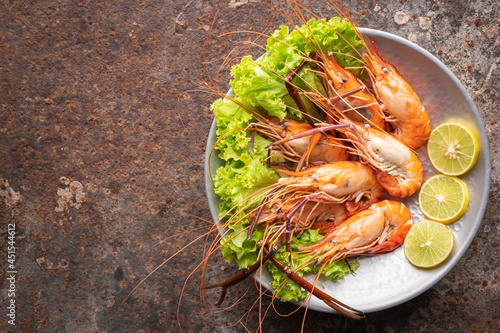steamed giant freshwater prawns with lettuce and lime in aluminium plate on rusty texture background with copy space for text, top view, river prawn