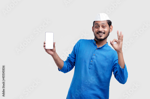 Young indian farmer showing smartphone and giving expression on white background.