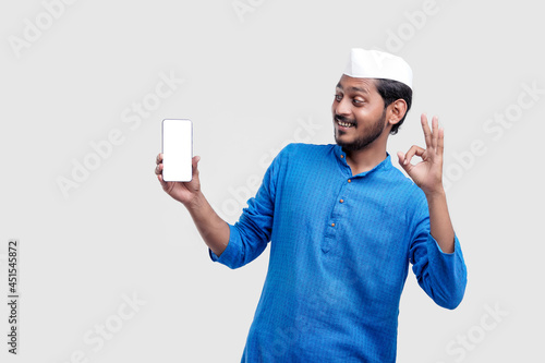 Young indian farmer showing smartphone and giving expression on white background.