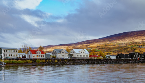 Rows of unique Icelandic building lining up between the mountain range and the lake on a autumn afternoon. Akureyri, Iceland