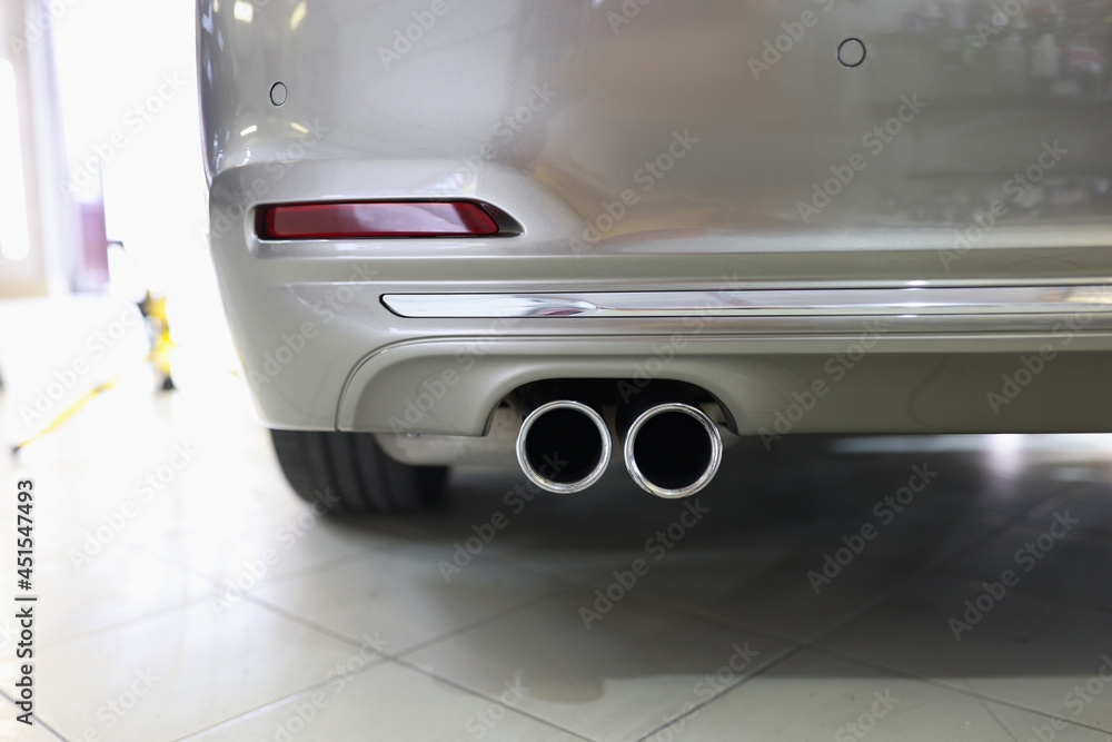 Exhaust pipe and back of new car in car service closeup