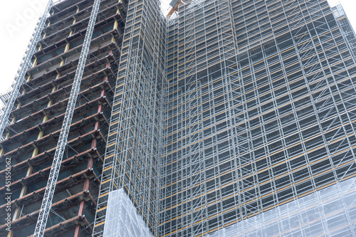 Scaffolding and metallic equipment around a high-rise building construction. No people  day light  outdoors.