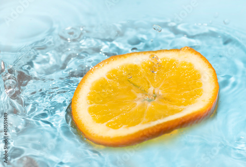 Fototapeta Naklejka Na Ścianę i Meble -  falling orange skin splashing water on a blue background