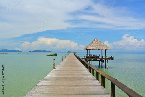 Long way plank pier to sea and small hut beside. Seascape against blue sky white clouds. Koh Mak island, Trat Province, Thailand. Postcard, Poster, Billboard, Wallpaper, Backdrop, Tourism Concept.