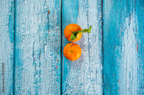 Two ripe tangerines viewed from the top on wooden blue plank table with peeling paint