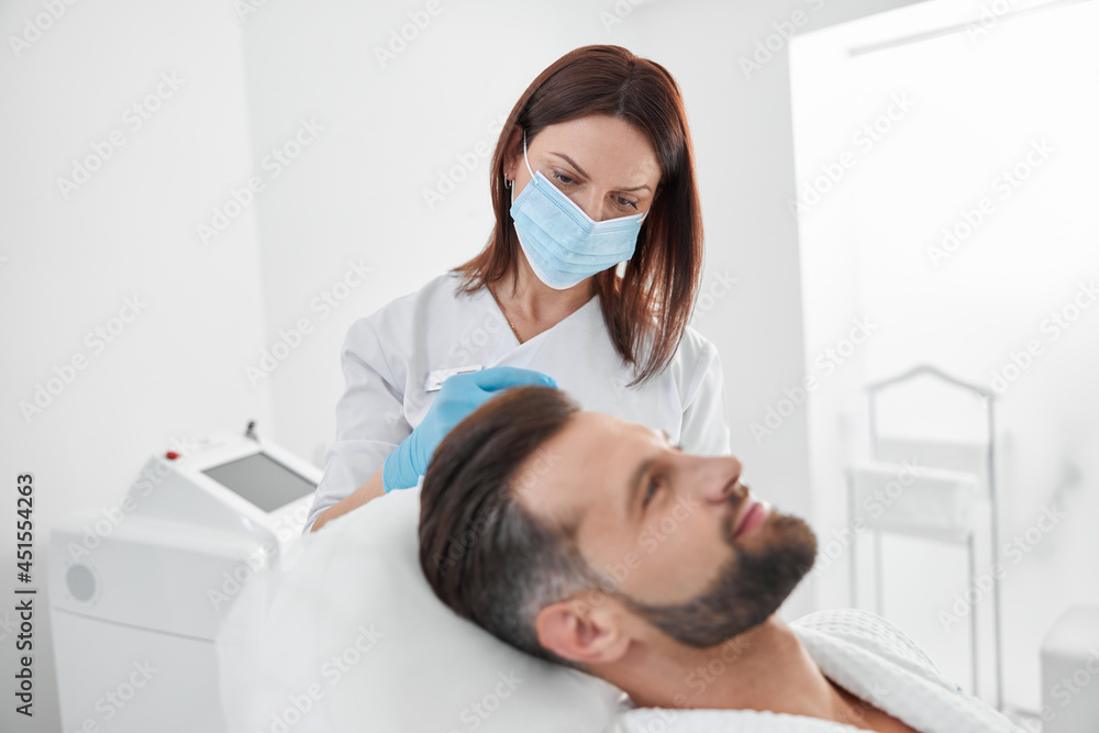 Beautician with mask does injection to man patient during antiaging meso therapy procedure in clinic Beautician with mask does injection to man patient during antiaging meso therapy procedure in clinic