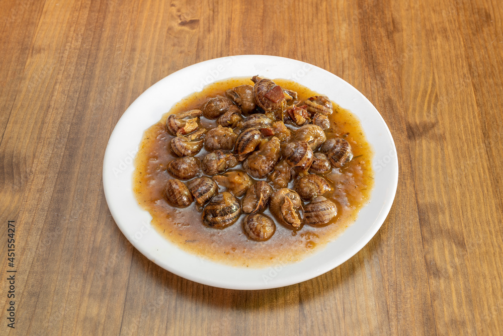 Typical Spanish recipe of snails stewed in sauce presented in a Madrid tapas restaurant Typical Spanish recipe of snails stewed in sauce presented in a Madrid tapas restaurant